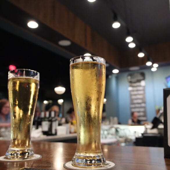 A pale, exceptionally clear beer in a tall glass at a bar.