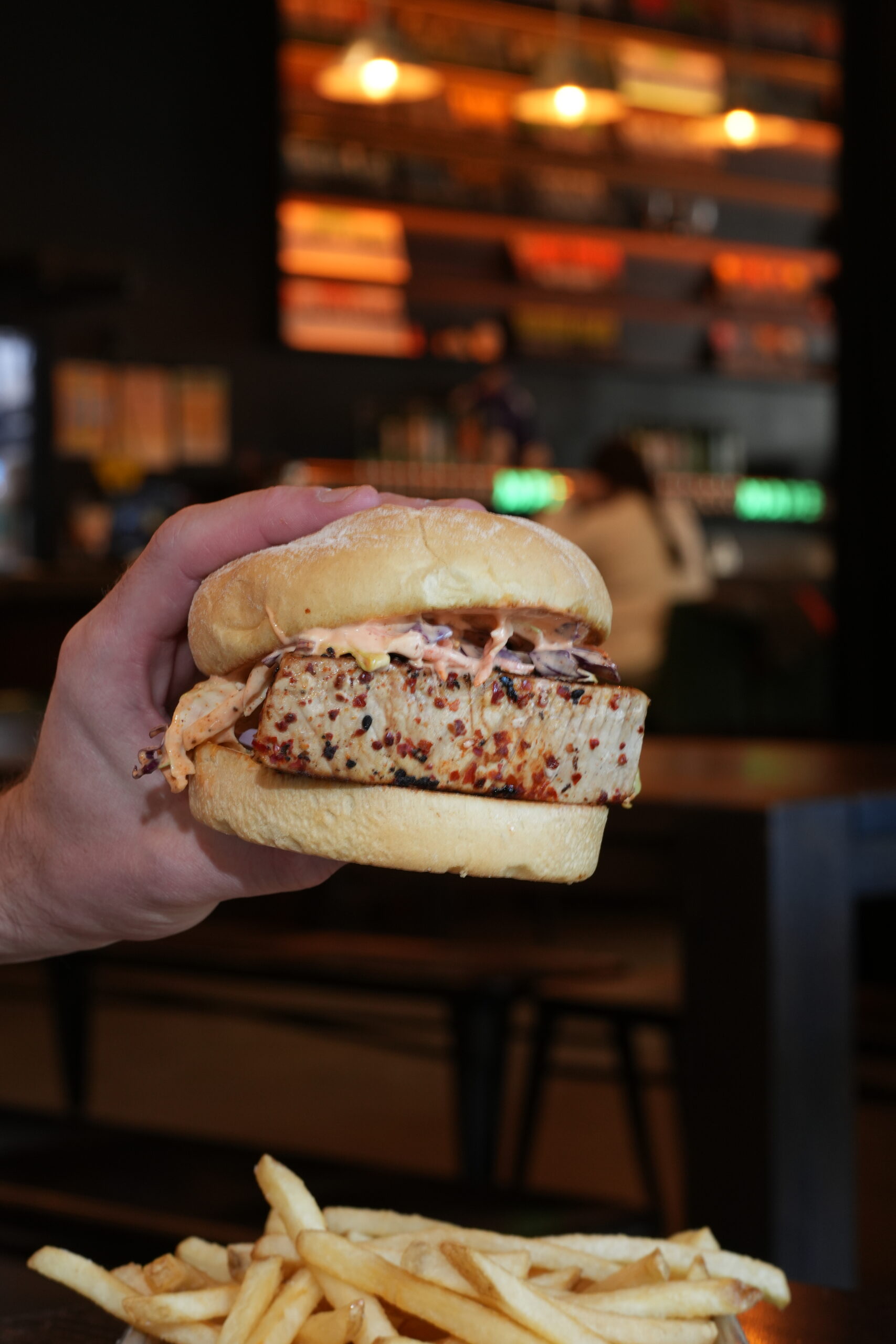 A hand holding a seared tuna sandwich.